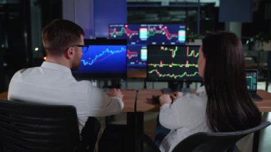 Ticaret ekibi hisse senedi ticareti yapıyor. Çoklu bilgisayar ekranlarındaki grafiklere, indekslere ve numaralara bakan borsa simsarları. Ticaret ofisinde iş arkadaşları tartışılıyor.
