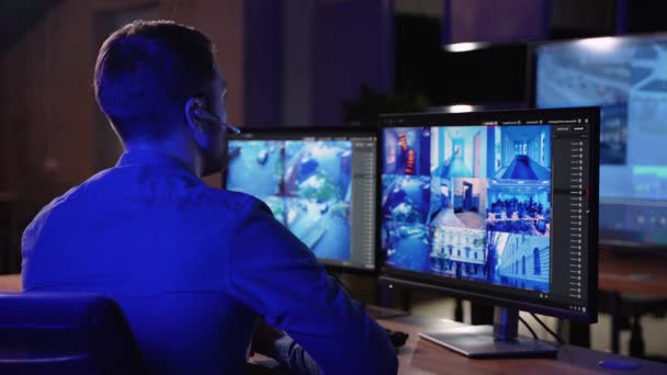 セキュリティガードは 監視センターで監視Cctvビデオフッテージを搭載したコンピュータで動作し ビッグデジタル画面上で複数のカメラを搭載しています 従業員がビッグデータでディスプレイの前に座る — ストック動画