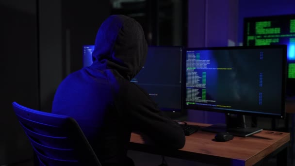 危险的连帽的黑客闯入政府数据服务器和感染病毒的系统 他的藏身之处地方都有黑暗的气氛 多台显示器电缆无处不在 — 图库视频影像