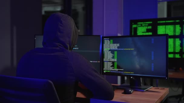 危险的连帽的黑客闯入政府数据服务器和感染病毒的系统 他的藏身之处地方都有黑暗的气氛 多台显示器电缆无处不在 — 图库视频影像