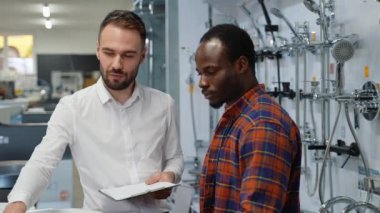 Satıcıyla birlikte siyah bir adam tesisat dükkanında lavaboyu seçiyor..