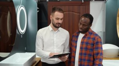 Genç Afrikalı Amerikalı bir adam yeni tuvalet mobilyalarını seçiyor.