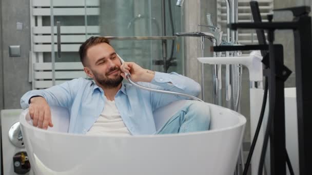 おかしい男のバイヤーは店の風呂で横たわっている電話を模倣します — ストック動画