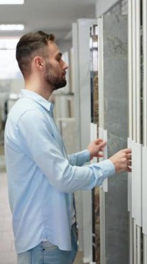 Yakışıklı bir adam evdeki seramik fayansları seçiyor.