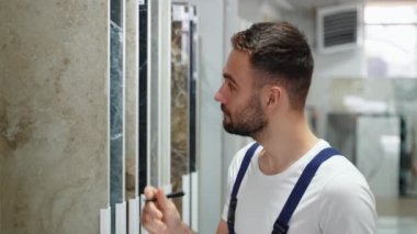 Erkek işçi, satış müdürü inşaat mağazasında döşeme envanteri çıkarıyor..