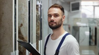 Erkek işçi, satış müdürü inşaat mağazasında döşeme envanteri çıkarıyor.