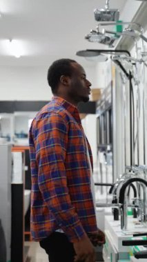 Afrikalı bir adam bir tesisat dükkanında banyo banyosu karıştırıcısı seçiyor.