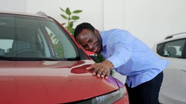 Zenci adam satın almadan önce yeni bir arabayı inceler.