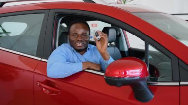 Afro-Amerikalı bir adam araba galerisinden yeni bir araba alıyor.