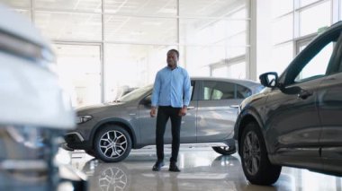 Afro-Amerikalı bir adam araba galerisinden yeni bir araba alıyor.