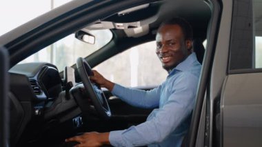 Afro-Amerikalı bir adam araba galerisinden yeni bir araba alıyor.