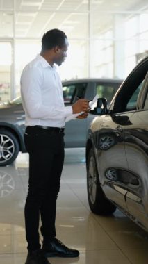 Gerekli tüm bilgiler hazırlanıyor. Afrikalı Amerikalı satış müdürü yeni arabaların envanterini yapıyor.