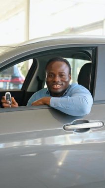 Araba galerisini ziyaret ediyorum. Yakışıklı siyah alıcı yeni arabasının anahtarını tutuyor, kameraya bakıyor ve gülümsüyor.