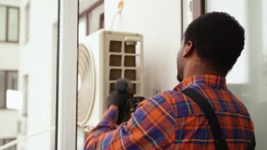 Afrikalı Amerikalı erkek teknisyen içeride klima tamir ediyor..