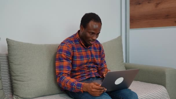 在视频电话会议上与同事交谈的黑人男子面带微笑地在书上写着会议便条 男子使用电脑膝上型计算机上网开会 — 图库视频影像