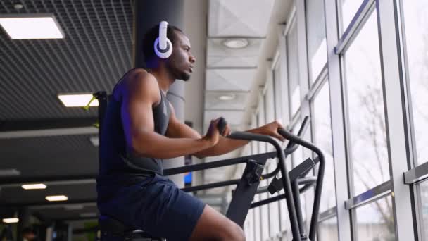Afro Amerikaanse Man Met Hoofdtelefoon Doet Cardiotraining Stationaire Luchtfiets Machine — Stockvideo