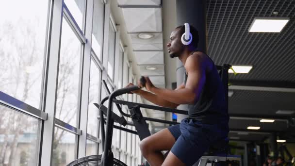 Afričan Američan Sluchátky Dělat Kardio Školení Stacionární Stroj Kolo Ventilátorem — Stock video