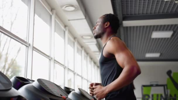 ジムでトレッドミルを実行しているスポーツウェアの若いアフリカ系アメリカ人男性 — ストック動画