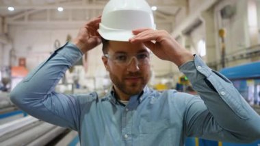Kendine güvenen mühendis üretim hattına koruyucu bir kask takıyor..
