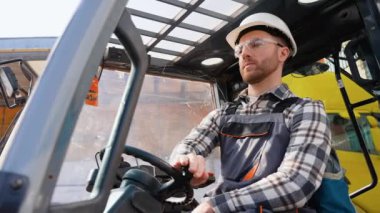 Depo işçisi forklift yükleyicisi kullanıyor..