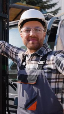 Forklift yükleyicisinin yanında gülümseyen depo işçisinin portresi