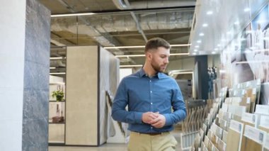 Yakışıklı adam lüks mağazada yürüyor ve fayans seçiyor..