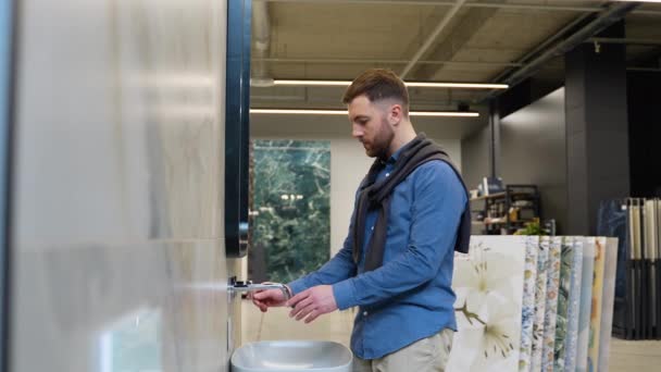一个英俊的男人在豪华水暖店选择新的浴室家具 — 图库视频影像