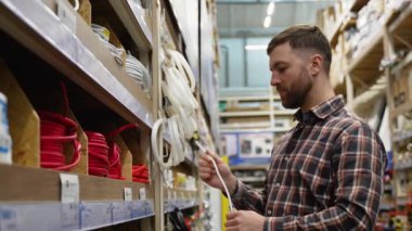 Bir adam bir hırdavatçıda elektrik veya ethernet kablosu satar..