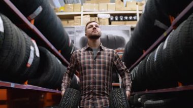 Lastik mağazasında yürüyen bir adam araba için iki yeni lastikle.