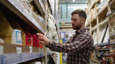 Bir adam bir hırdavatçıda elektrik veya ethernet kablosu satar.