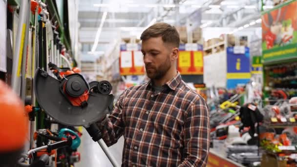 Hombre Elige Una Podadora Eléctrica Para Cortar Césped Una Tienda — Vídeo de stock