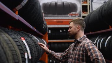 Bir adam lastik dükkanında yeni bir lastik seçer..