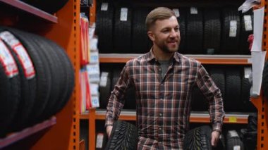 Lastik mağazasında yürüyen bir adam araba için iki yeni lastikle.