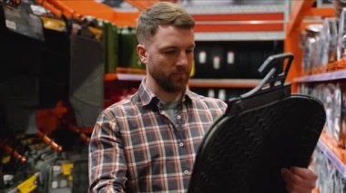 Tamirhanede bir adam yeni bir paspas seçiyor..