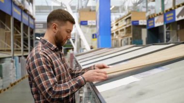 Dükkanda ahşap döşemeyi seçen bir adam..