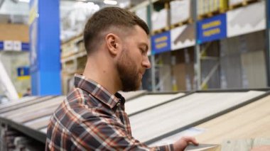 Bir adam bir mağazada farklı renkte ve tipte yerlere bakar..