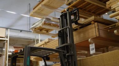 Forklift yükleyicisiyle kereste yükleyen üniformalı depo işçisi..