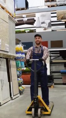 Mağazadaki forklift yükleyicisine binen komik bir depo çalışanı.