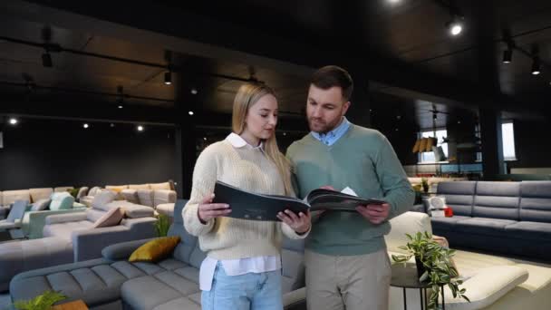Junges Paar Wählt Sofa Katalog Luxus Möbelhaus — Stockvideo