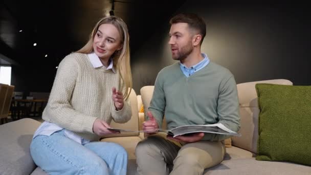 年轻夫妇在豪华家具店的目录上选择沙发 — 图库视频影像