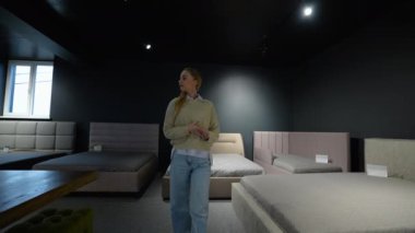Genç bir kadın lüks mobilya dükkanında yeni bir kanepe seçiyor..