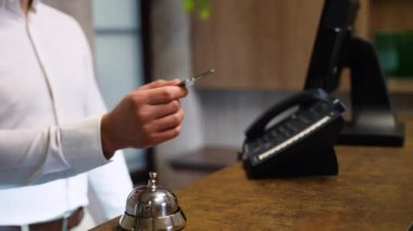 Resepsiyonist otel lobisindeki konuğun anahtarlarını verir..