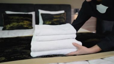 Havluları yatağın üstüne koyarak otel hizmetçisi