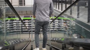 Hırdavatçıda yürüyen merdivende tramvayı olan bir adam.