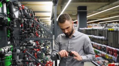 Hırdavatçıda bir adam yeni bir tornavida seçer.