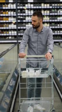 Hırdavatçıda yürüyen merdivende alışveriş arabası olan bir adam.