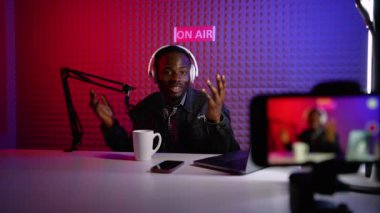 Vlog 'u kaydetmek için mikrofon ve kulaklık kullanan Afrikalı Amerikalı bir vlogger. Sosyal medya podcast 'i için modern ekipmanlarla çekim yapan olumlu bir adam. Stüdyoda blogger kaydı