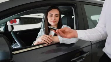 Araba satıcısı yeni arabanın anahtarını genç ve çekici kadına veriyor. Şimdi rüyası gerçek oldu. Genç bir kadın yeni arabasının anahtarlarını alıyor.