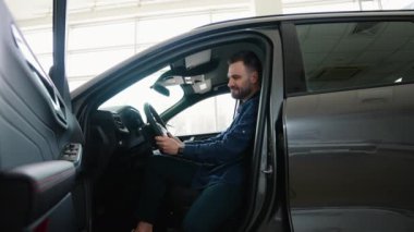 Müşteri yeni araba seçiyor ve araba galerisinden almadan önce kontrol ediyor. Bir adam yeni bir araba alır.