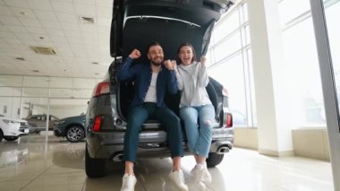 Mutlu evli çift yeni bir araba almanın sevincini yaşıyor. Araba alan genç bir çift. Galeriye başarılı bir ziyaret. Mutlu genç çift aile için yeni bir araba seçer ve alır.